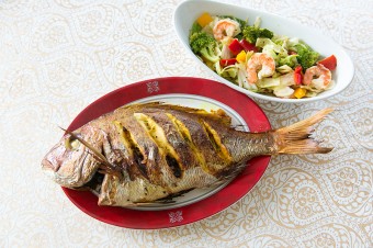 元日の前夜、家族で集まって食べる魚の詰め物。ドライフルーツが鯛のお腹にたっぷり！　サラダはにんにくとごま油の香りに食欲をそそられる。