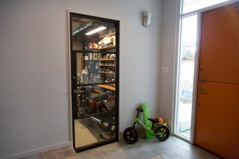 玄関のガレージのドアはガラスに。家に帰るとガレージの愛車たちが出迎えてくれる。