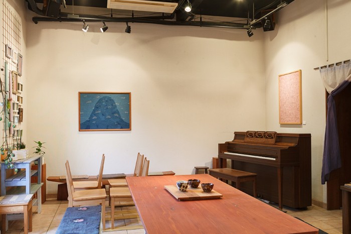 柴原さんの作品やニューヨークスタインウエイアップライトのリメイクピアノが並ぶギャラリー。壁のテキスタイルの額は妻の柴原規子さんの作品。