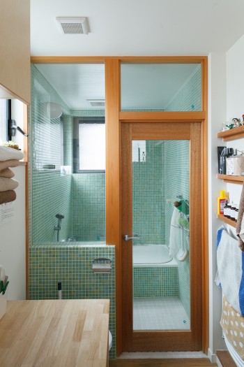 グリーンのグラデーションのタイルが美しいバスルーム。トイレ・洗面室との間をガラス張りにすることで、開放感たっぷり。