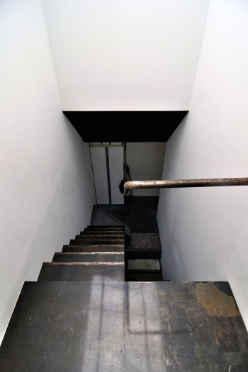 白い壁と黒い壁による抽象的な構成の中でスチールの材質感が強く感じられる階段。