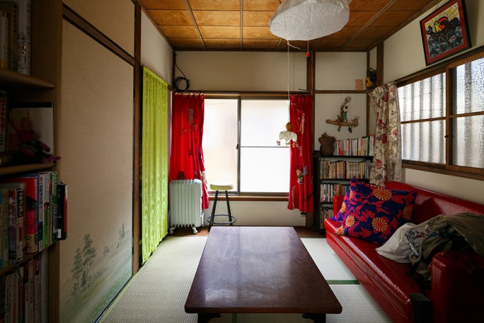 1階の間取りはこちらの4畳半とトイレのみ。畳にソファやカーテンの赤がよく映える。