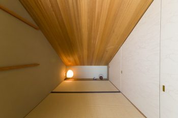 踊り場の奥にある３畳ほどの和室。屋根の勾配なりに傾斜した収納は、隅々まで活用。天井にラワン材、ふすまには江戸からかみを使用。