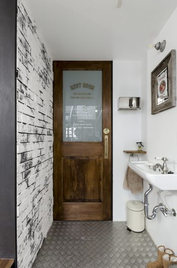 トイレの扉の文字は勇介さんデザインのカッティングシート。左の壁は黒いブリックタイルを張った上から漆喰を塗った。