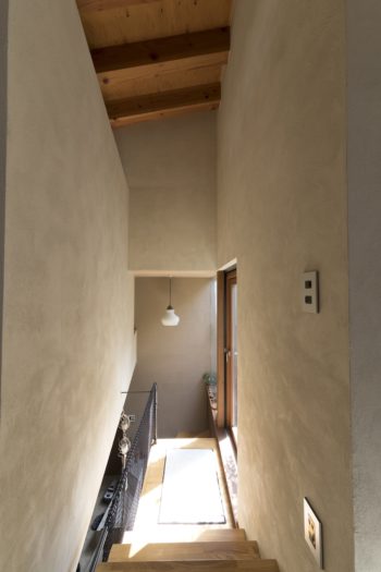 ペンキに砂を混ぜ、表情豊かな壁に仕上げている。１階に降りる階段の途中からも、中庭のテラスに出ることができる。