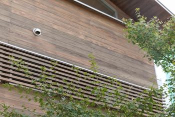 窓につけた木製のルーバーは、アルミサッシの無機的な雰囲気を消す意匠的な役割と、目隠しや日差しカットという実用的な役割を併せ持つ。