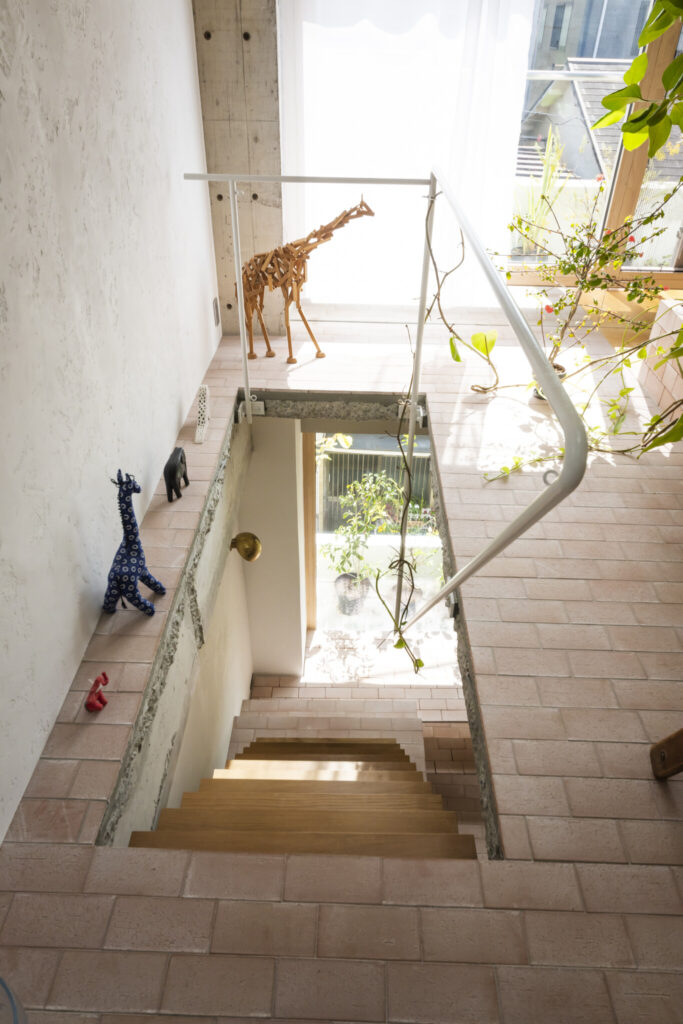 新設した階段を３階から見下ろす。間田邸には、ケニアや北欧などを旅した際に購入した動物のオブジェがアクセントに使われている。木製のキリンは望月勤氏の作品。