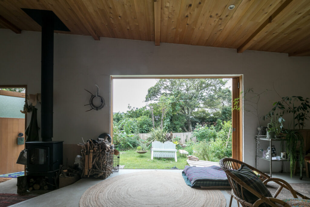 幅３mの引き込み窓を全開にすると、庭と一体感を楽しめる大開口となる。高さのある天井には杉材を使用。
