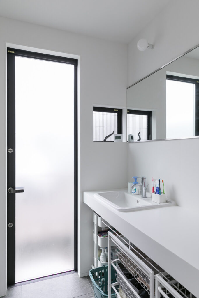 1階洗面スペース。白と黒のコントラストがシンプルながらも洗練された印象を与える。